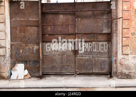 A no parking sign painted onto a rusty garage door in Havana, Cuba. Stock Photo