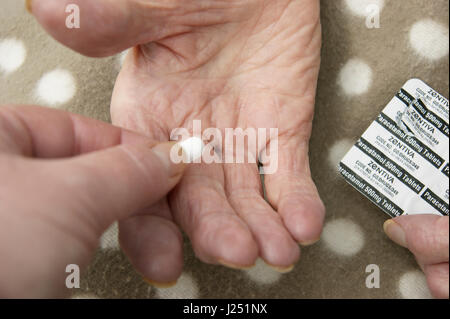 Female carer /daughter giving a tablet to a disabled elderly woman (mother) Stock Photo
