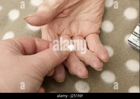 Female carer /daughter giving a tablet to a disabled elderly woman (mother) Stock Photo