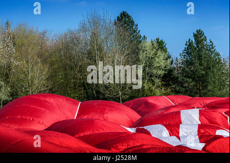 HOT AIR BALLOON deflating against a backdrop of trees and sky Stock Photo
