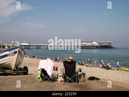 Cromer Pier and Beach, with mature couple seated picnicking on promenade, North Norfolk Coast, Cromer, Norfolk, England, UK Stock Photo