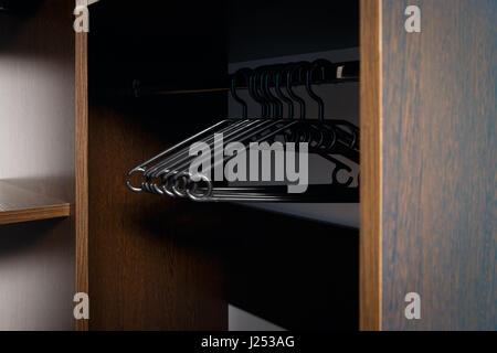 Black plastic clothes hangers are hung in an empty cabinet Stock Photo