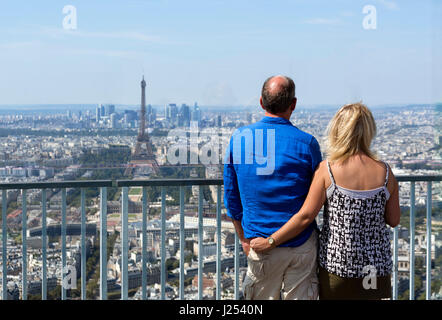 Couple on the observation deck at the top of the Tour Montparnasse, looking towards the Eiffel Tower and La Defense, Paris, France Stock Photo