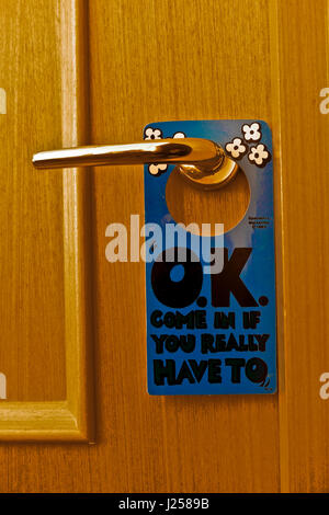 Come in, humorous enter sign on a hotel bedroom closed door. “OK come in if you really have to”. Close up, detail. Stock Photo