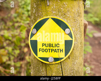 a public footpath sign in the forest leading the way on a trail in spring while walking Stock Photo