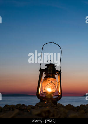 Old style petrol lamp lighting on the beach close to the calm sea Stock Photo