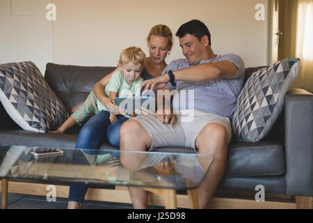 Happy parents with son using digital tablet on sofa at home Stock Photo