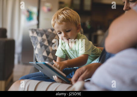 Boy using digital tablet by parents in living room at home Stock Photo