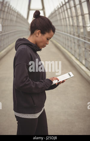 Side view of woman using digital tablet on bridge Stock Photo