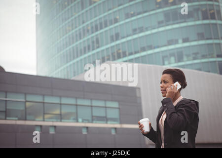 Businesswoman talking on mobile phone against modern building Stock Photo
