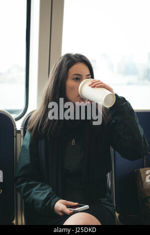 Beautiful woman drinking coffee while sitting in train Stock Photo