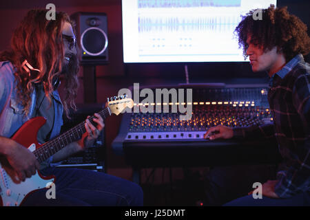 Portrait of male audio engineer playing electric guitar in recording studio Stock Photo