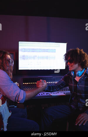 Male audio engineers shaking hands in recording studio Stock Photo