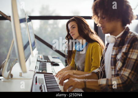Audio engineer playing electric keyboard in recording studio Stock Photo