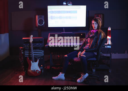 Portrait of female audio engineer sitting in recording studio Stock Photo