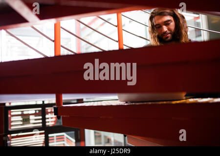 Sound engineer using laptop on stairs in office Stock Photo