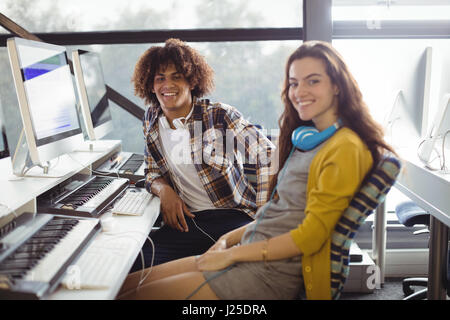 Portrait of smiling male and female sound engineer sitting in office Stock Photo