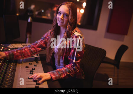Portrait of female audio engineer using sound mixer in recording studio Stock Photo