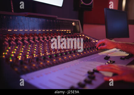 Hands of male audio engineer using sound mixer in recording studio Stock Photo