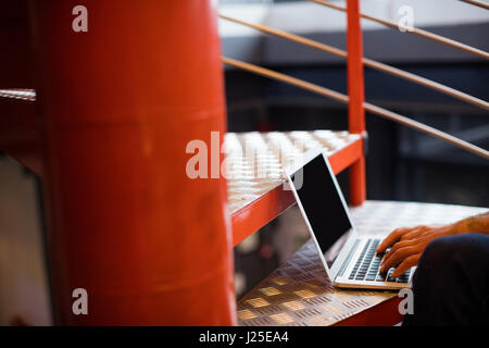 Sound engineer using laptop on stairs in office Stock Photo