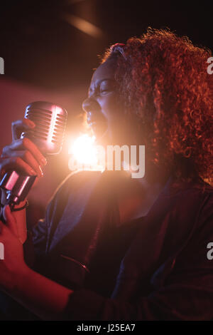 Woman singing on retro microphone in recording studio Stock Photo