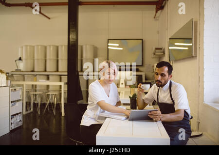 Male and female barista having coffee while using digital tablet in coffee shop Stock Photo