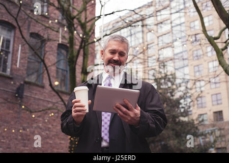 Low angle view of businessman using tablet while standing in city Stock Photo