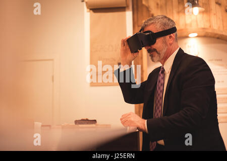 Businessman using virtual reality simulator while sitting at table Stock Photo