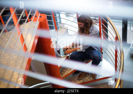 Sound engineer using laptop on stairs in office Stock Photo