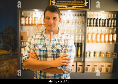 Portrait of confident salesman standing against honey bottles on shelves Stock Photo