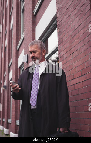Businessman using mobile phone while standing against building in city Stock Photo