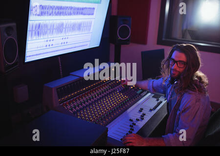 Portrait of male audio engineer using sound mixer in recording studio Stock Photo