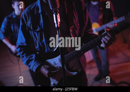 Mid-section of guitarist playing electric guitar in recording studio Stock Photo