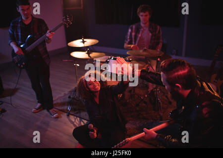Band mates giving high five to each other in recording studio Stock Photo