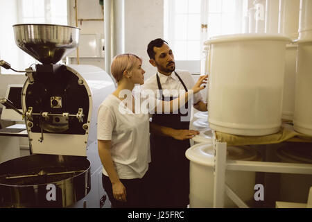 Male and female barista checking coffee beans quantity level in coffee shop Stock Photo