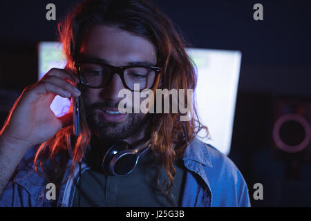 Male audio engineer talking on mobile phone in recording studio Stock Photo