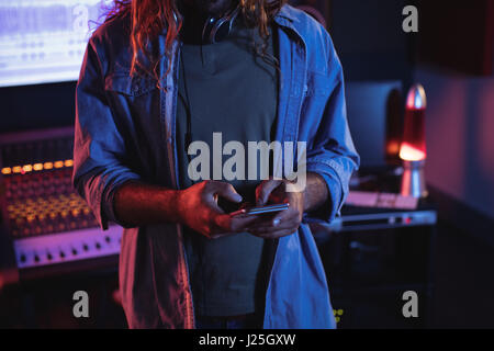 Male audio engineer using mobile phone in recording studio Stock Photo