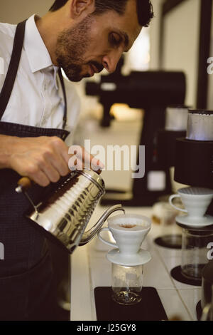 Barista pouring hot water through funnel in coffee shop Stock Photo