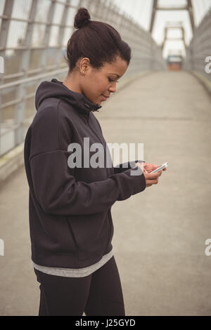 Side view of woman using mobile phone on bridge Stock Photo
