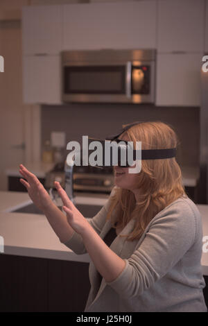 Woman gesturing while enjoying virtual reality simulator in kitchen at home Stock Photo