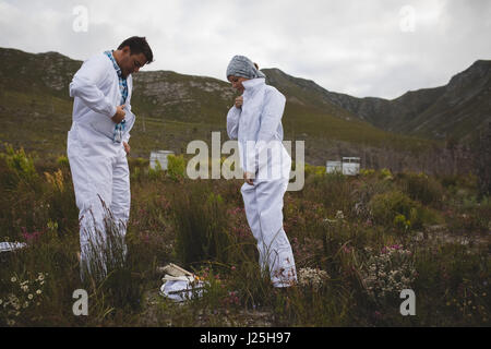 Male and female beekeepers wearing clothing on field