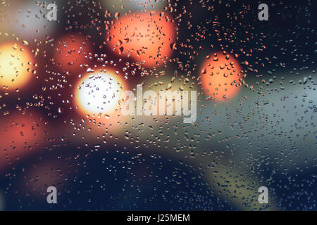Raindrops on a car window with beautifully blurred background of street traffic lights Stock Photo