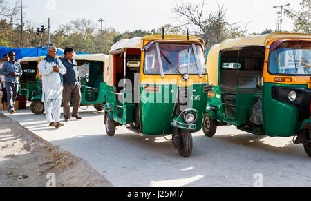 Typical green and yellow tuk-tuk taxis (three wheeler auto rickshaws) parked waiting on the roadside outside Delhi station, Delhi, Punjab, India Stock Photo