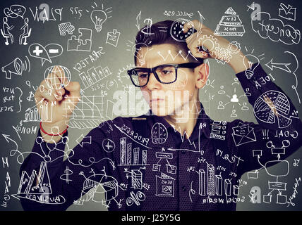 Smart thoughtful guy writing high school maths and science formulas on blackboard Stock Photo