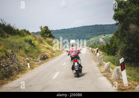 Young Woman Riding Motor Scooter Through Island of Vis, Croatia Stock Photo