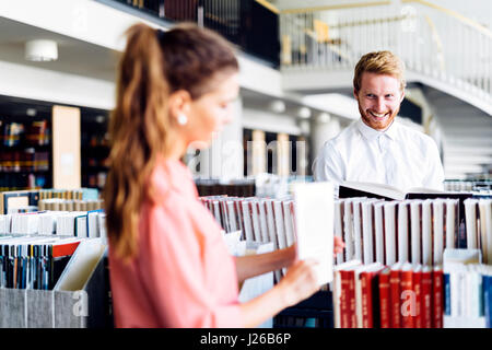 Beautiful happy students studying and flirting in a modern library Stock Photo