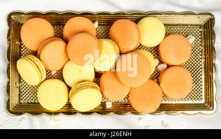 Stack of orange and yellow macaroon biscuits isolated on white. Stock Photo