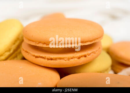 Stack of orange and yellow macaroon biscuits isolated on white. Stock Photo