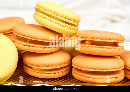 Stack of orange and yellow macaroon biscuits isolated on white. Stock Photo