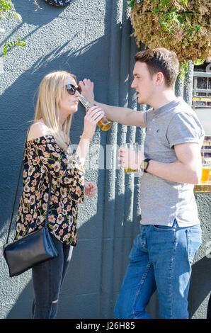 A couple stand outside a pub enjoying a drink and a chat. Stock Photo